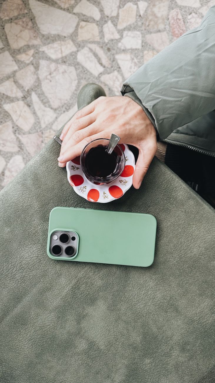 man sitting at the table with a glass of tea and a smartphone