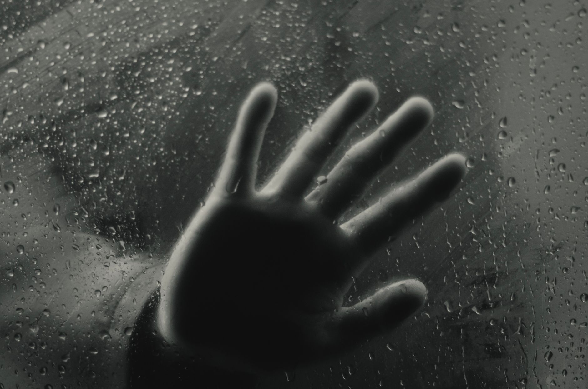 crop person touching glass wall with water drops