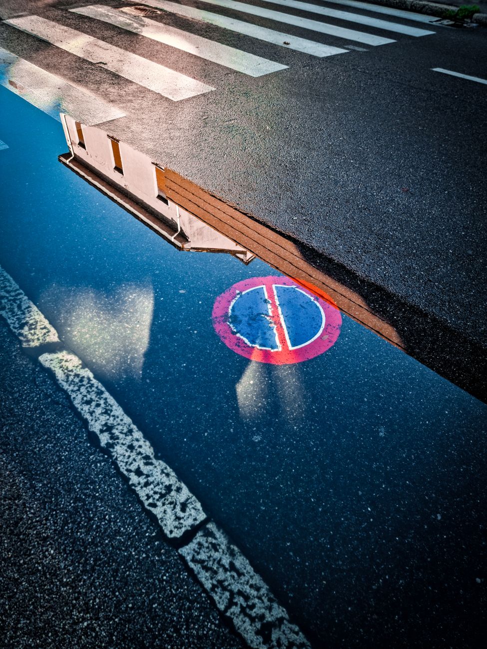 a reflection of a street sign in a puddle