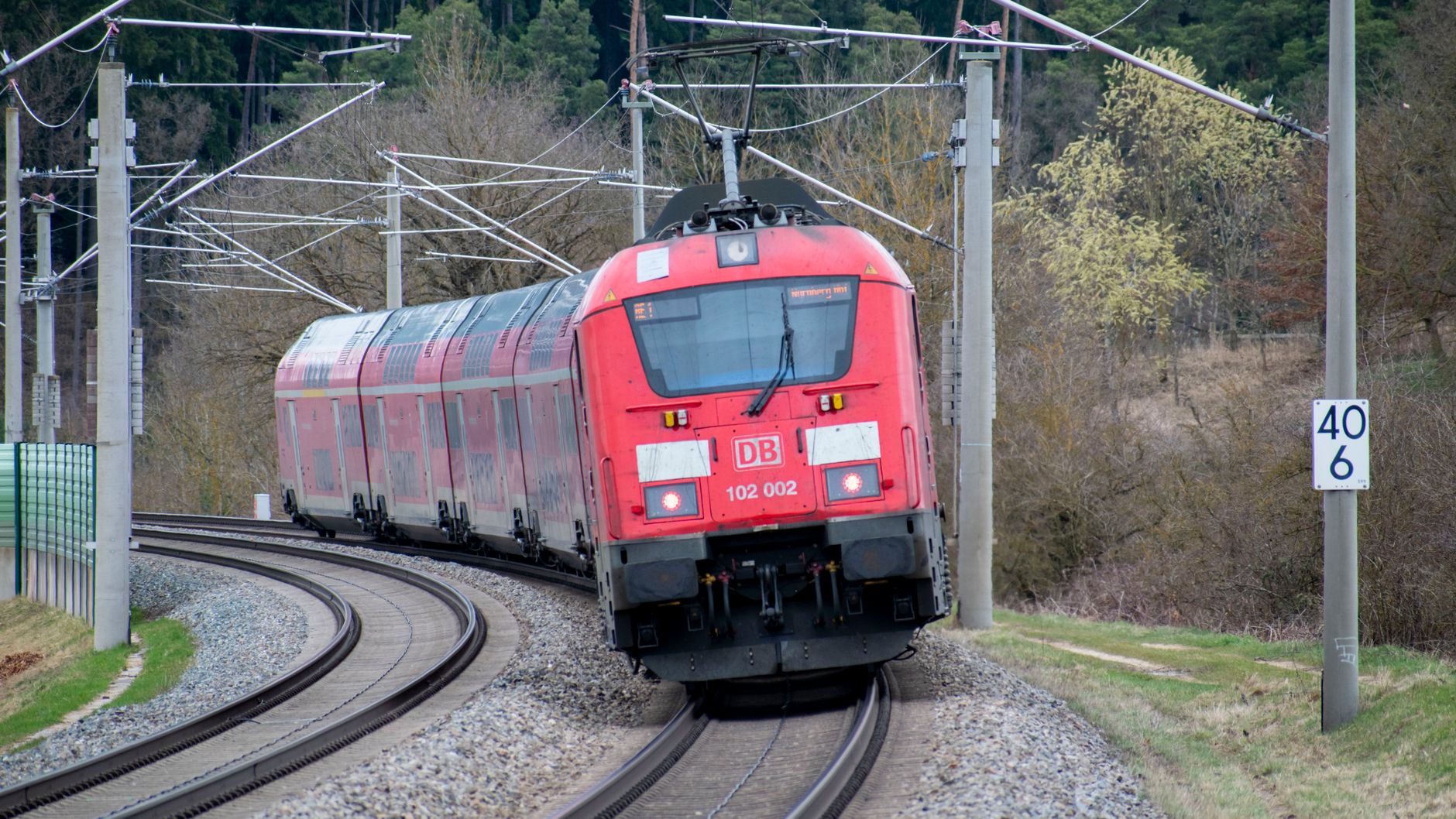 red train traveling on curved railway track outdoors