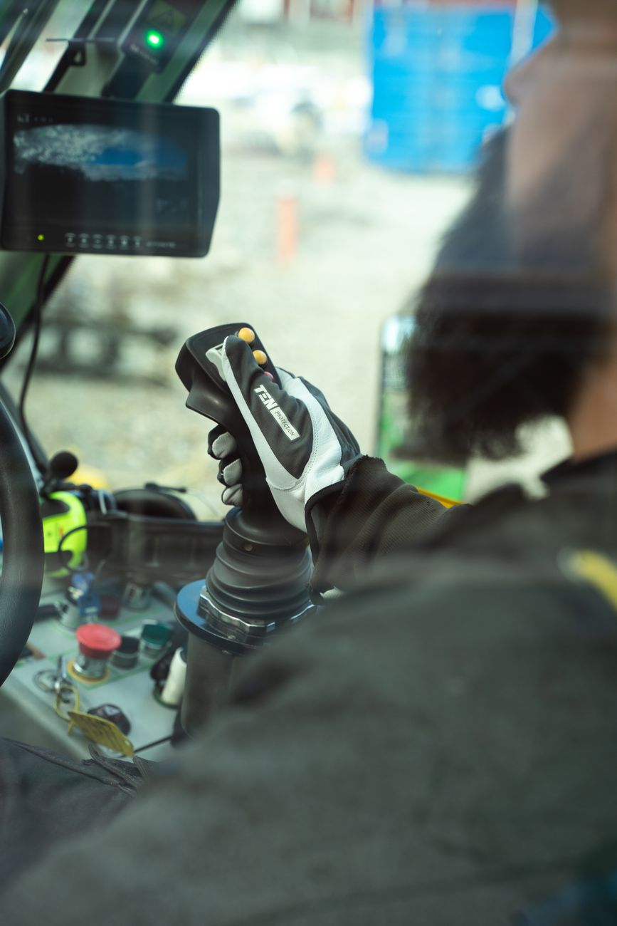 hand of a bearded man driving a construction vehicle