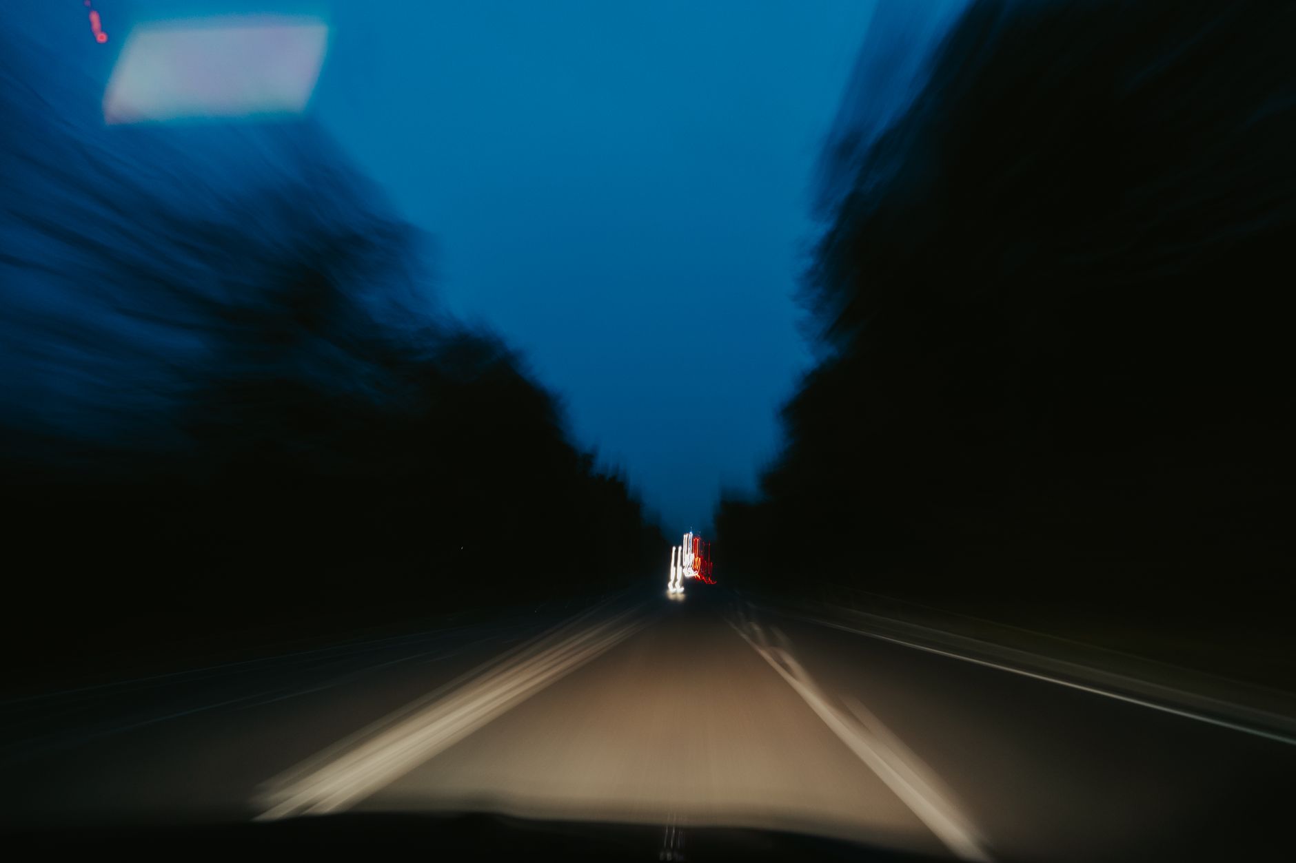 blurry photo of a street at night seen from an inside of a car