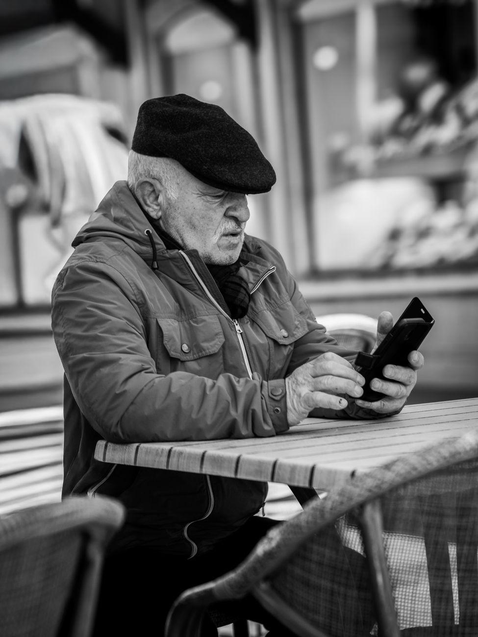 senior man using smartphone at outdoor cafe