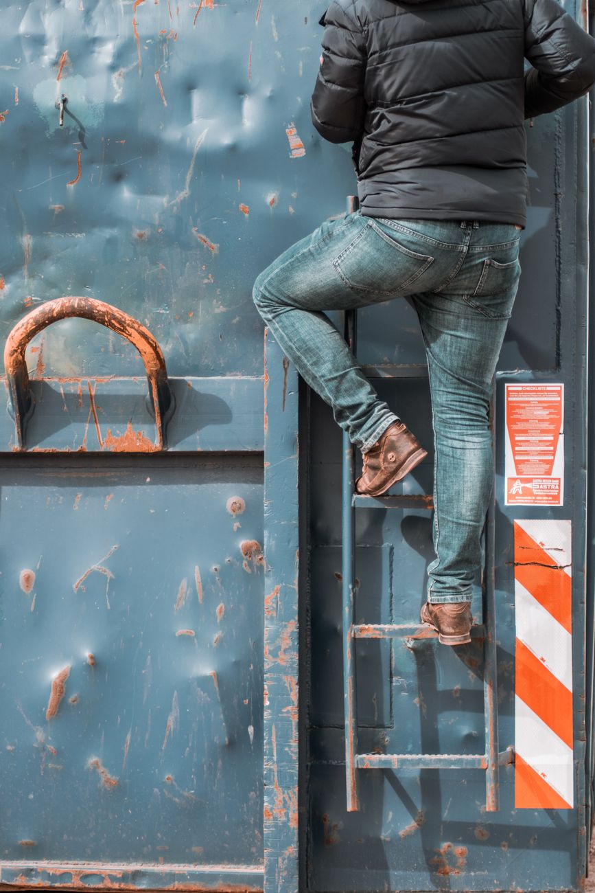man in jeans posing on ladder of container
